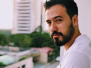 A bearded man standing on a balcony looking inside