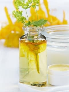 Jojoba oil is in a glass bottle with few leaves on the top