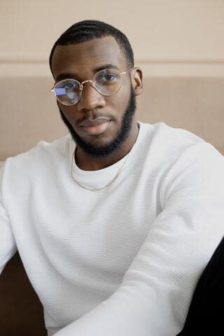 A black man with specs sitting with no impression
