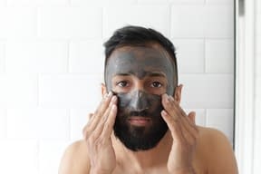 man cleansing his face with charcoal clenaser